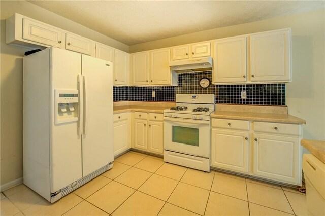 kitchen featuring tasteful backsplash, white appliances, light countertops, and under cabinet range hood