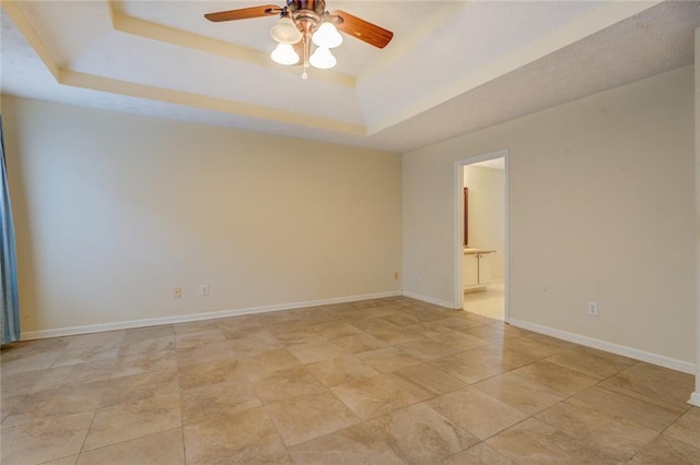 empty room featuring ceiling fan, baseboards, and a raised ceiling