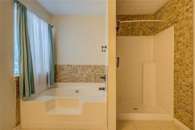 bathroom featuring a textured ceiling, a shower stall, a bath, and tile patterned floors