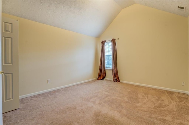 empty room with carpet, visible vents, vaulted ceiling, and baseboards