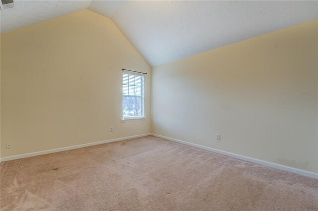 unfurnished room with lofted ceiling, baseboards, and carpet flooring