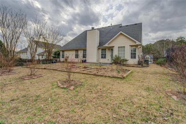 rear view of house with fence, a chimney, and a lawn