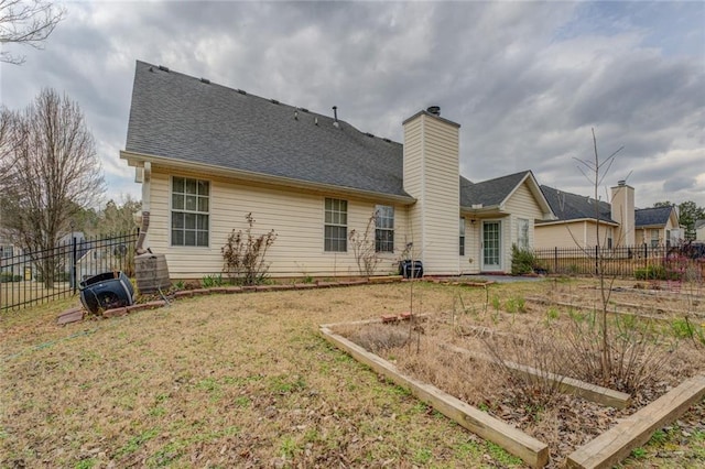 rear view of property featuring a yard, a chimney, fence, and roof with shingles