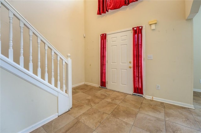 foyer entrance featuring stairway and baseboards