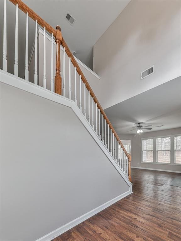 stairs featuring ceiling fan, wood-type flooring, and a towering ceiling