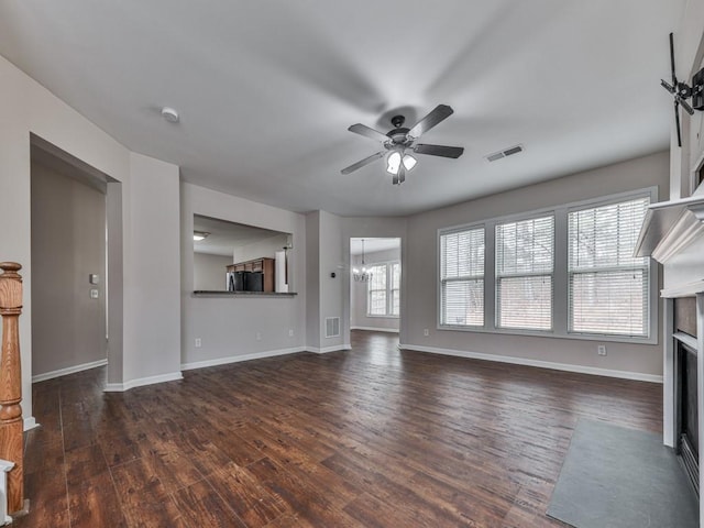 unfurnished living room with dark hardwood / wood-style flooring and ceiling fan with notable chandelier