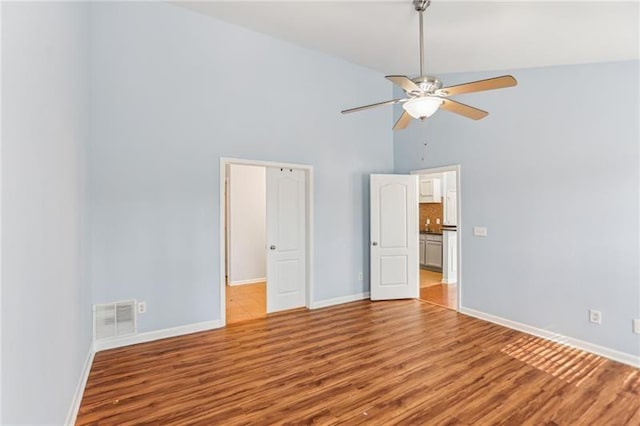 unfurnished bedroom featuring visible vents, wood finished floors, baseboards, and high vaulted ceiling