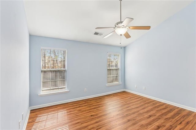 empty room with ceiling fan, baseboards, visible vents, and wood finished floors