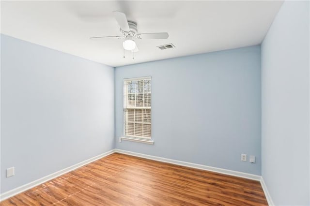 spare room featuring ceiling fan, baseboards, visible vents, and wood finished floors