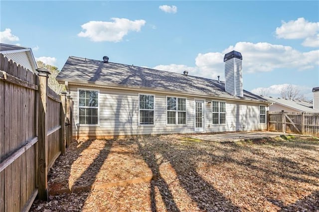 rear view of house featuring a patio, a chimney, and a fenced backyard