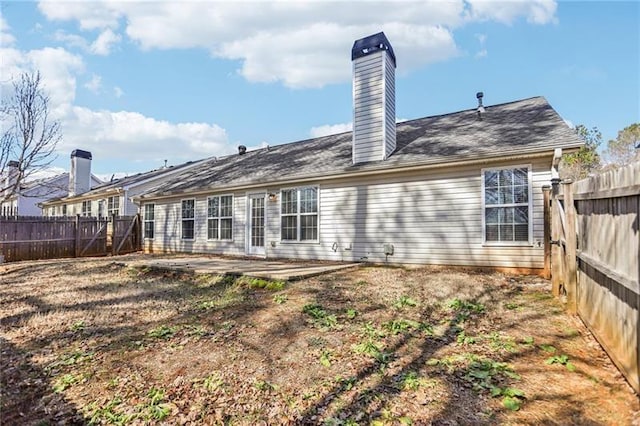 rear view of property featuring a chimney, a patio, and a fenced backyard