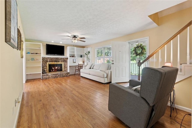 86 Sleepy Hollow Rd, Dahlonega, GA 30533 - living area with wood finished floors, a ceiling fan, a stone fireplace, stairs, and a textured ceiling