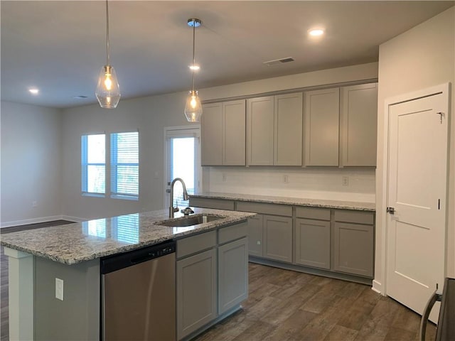 kitchen featuring stainless steel dishwasher, a kitchen island with sink, sink, and gray cabinetry