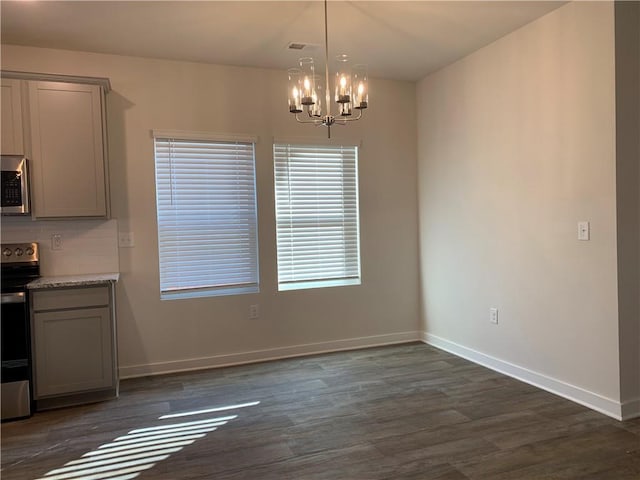 unfurnished dining area featuring dark hardwood / wood-style floors and a chandelier