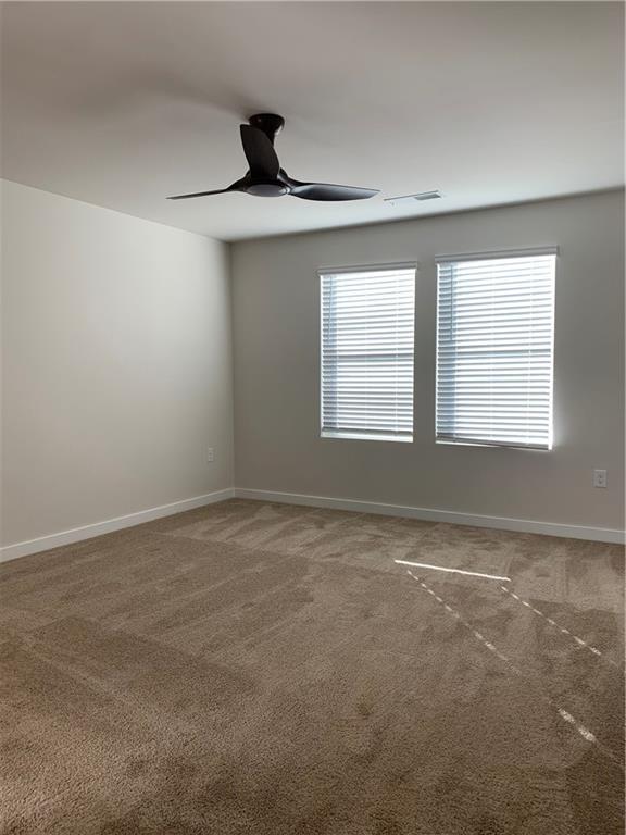 carpeted spare room with ceiling fan