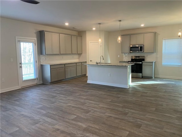 kitchen with sink, a center island with sink, gray cabinets, pendant lighting, and stainless steel appliances