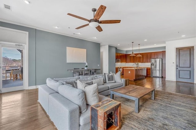 living room featuring dark hardwood / wood-style flooring, crown molding, and ceiling fan