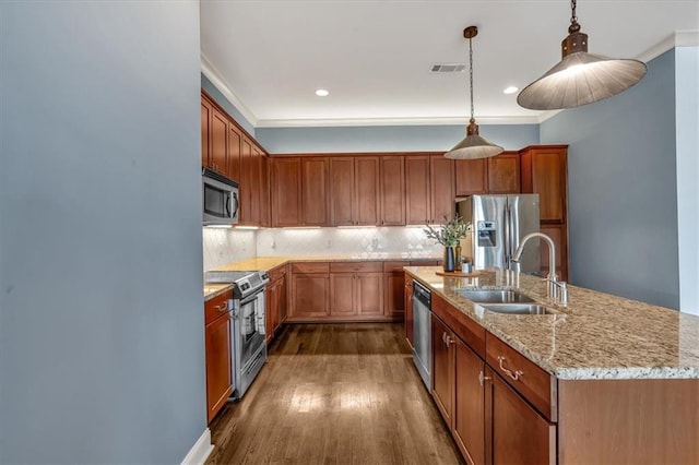 kitchen with hanging light fixtures, appliances with stainless steel finishes, sink, and a center island with sink