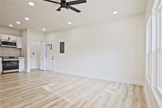 unfurnished living room with electric panel, light hardwood / wood-style flooring, and ceiling fan