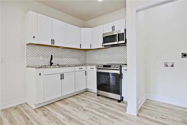 kitchen featuring appliances with stainless steel finishes, light hardwood / wood-style floors, white cabinetry, and sink