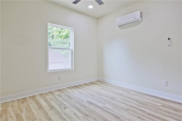 unfurnished room featuring light hardwood / wood-style floors, a wall mounted AC, and ceiling fan