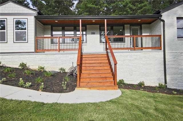 doorway to property featuring a lawn and covered porch