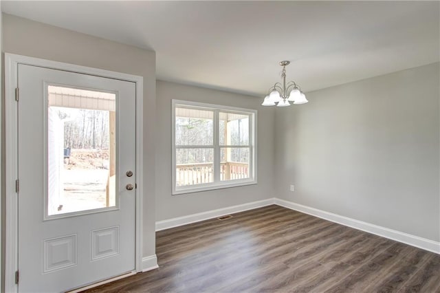 doorway to outside featuring a notable chandelier and dark wood-type flooring