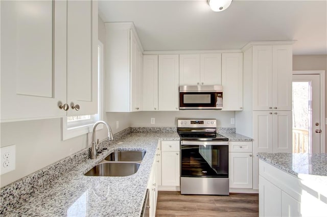 kitchen with white cabinetry, sink, stainless steel appliances, light stone counters, and plenty of natural light