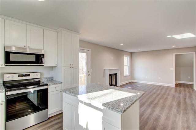 kitchen with light stone countertops, appliances with stainless steel finishes, light wood-type flooring, and white cabinetry