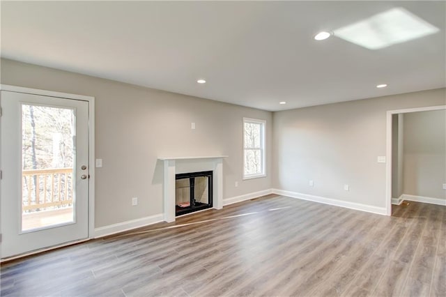 unfurnished living room featuring plenty of natural light and light hardwood / wood-style flooring