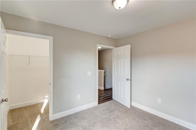 unfurnished bedroom with a walk in closet, light carpet, and a closet