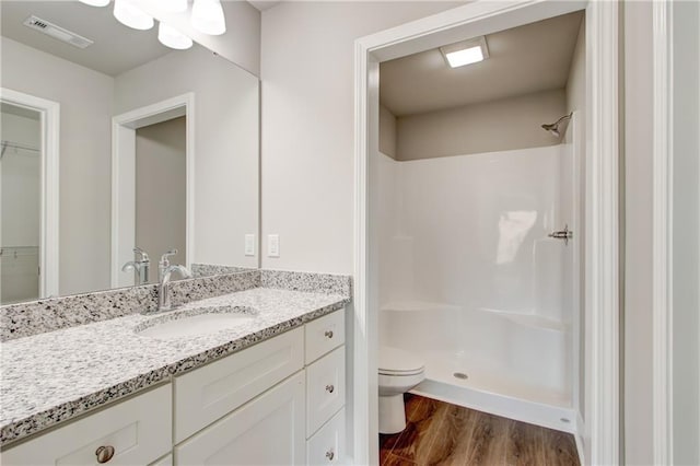 bathroom with toilet, hardwood / wood-style floors, vanity, and walk in shower