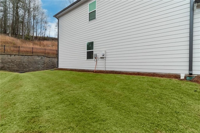 view of home's exterior with a lawn and fence