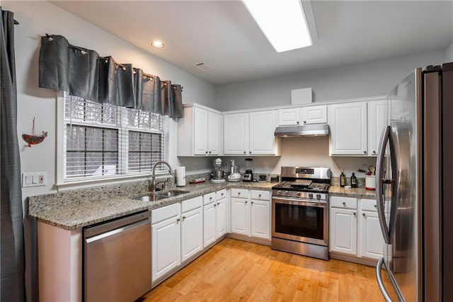 kitchen featuring stainless steel appliances, sink, stone counters, light hardwood / wood-style floors, and white cabinetry