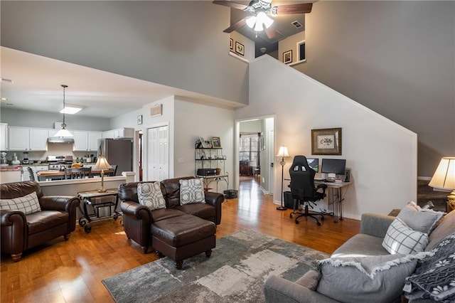 living room with ceiling fan, light hardwood / wood-style flooring, and a high ceiling