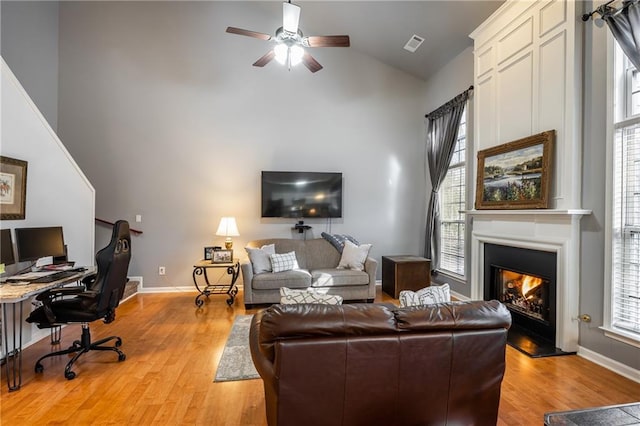 living room with light wood-type flooring, a wealth of natural light, and vaulted ceiling