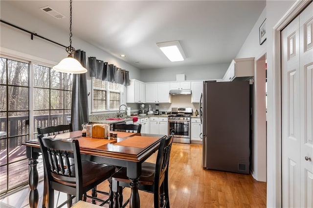 kitchen featuring pendant lighting, white cabinets, sink, light hardwood / wood-style flooring, and stainless steel appliances