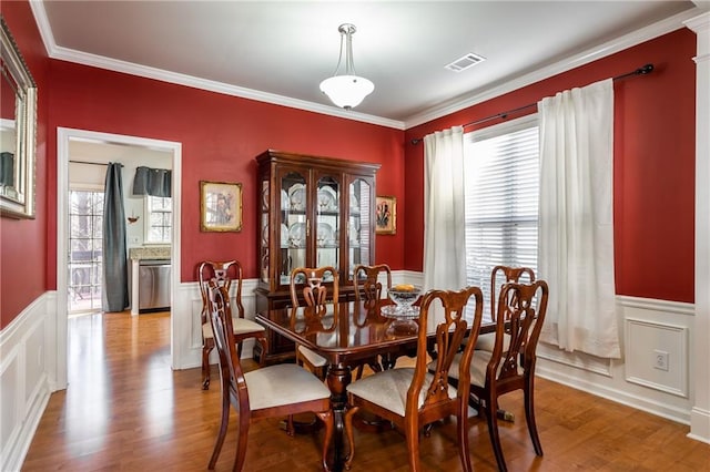 dining room with light wood-type flooring and crown molding