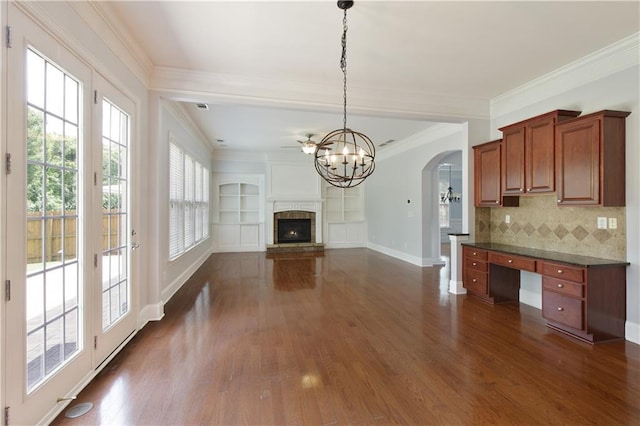 4652 Prater Way SE, Smyrna, GA 30080 - unfurnished living room featuring arched walkways, a chandelier, dark wood-style floors, ornamental molding, and a lit fireplace