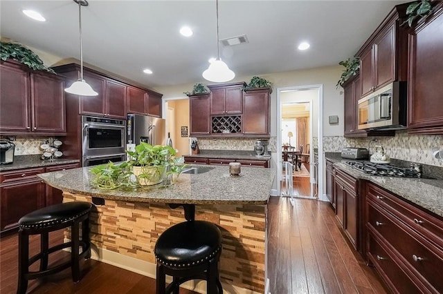kitchen featuring appliances with stainless steel finishes, decorative backsplash, dark wood-style flooring, and visible vents