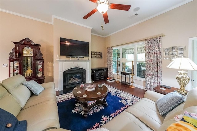 living room with visible vents, crown molding, a glass covered fireplace, wood finished floors, and a ceiling fan