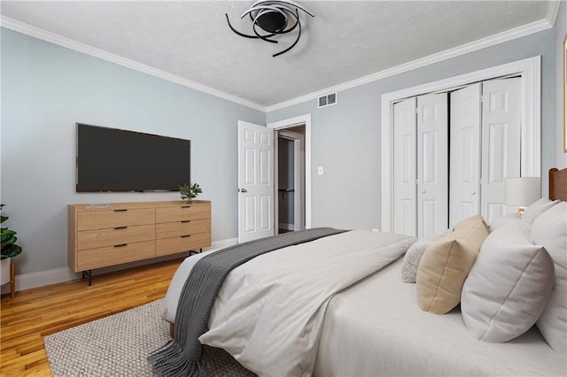 bedroom featuring a closet, hardwood / wood-style floors, a textured ceiling, and ornamental molding