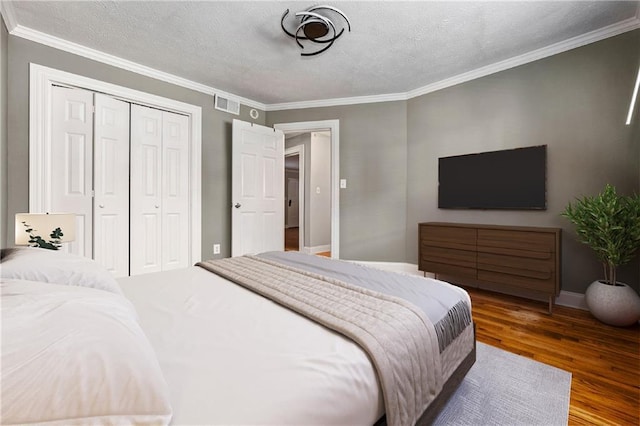 bedroom featuring hardwood / wood-style floors, a textured ceiling, a closet, and crown molding