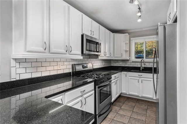 kitchen with backsplash, dark stone counters, sink, appliances with stainless steel finishes, and white cabinetry