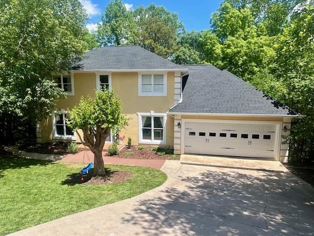 1536 Enota Ave, Gainesville, GA 30501 - colonial home featuring an attached garage, driveway, stucco siding, and a front yard