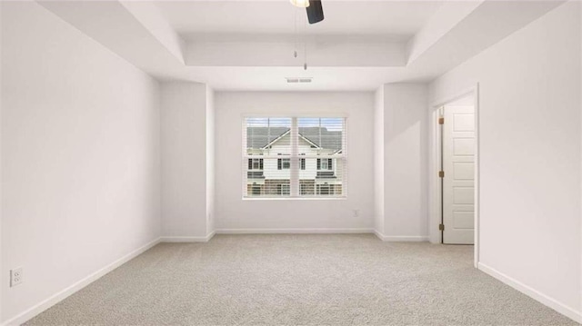 carpeted empty room with a tray ceiling and ceiling fan