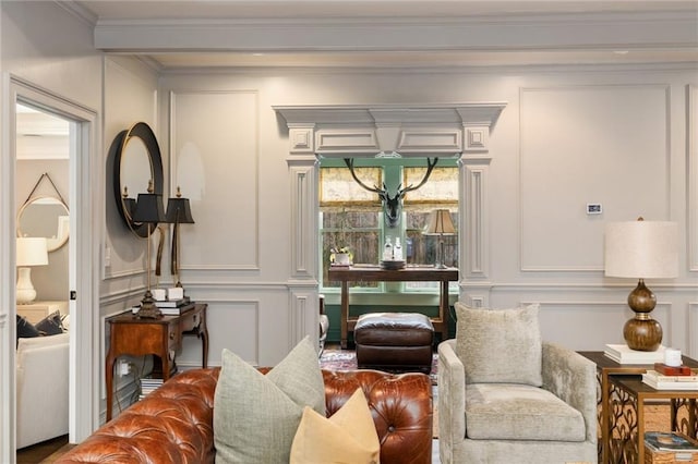 living area featuring decorative columns, a decorative wall, and crown molding