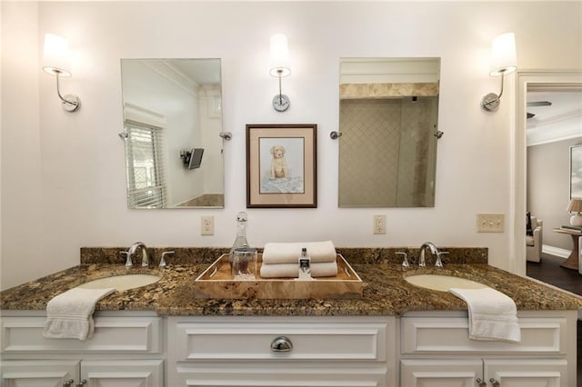 bathroom featuring a tile shower, double vanity, ornamental molding, and a sink