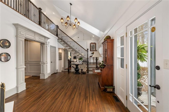 foyer entrance with high vaulted ceiling, a notable chandelier, wood finished floors, visible vents, and stairs