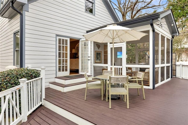 wooden terrace with outdoor dining space and a sunroom